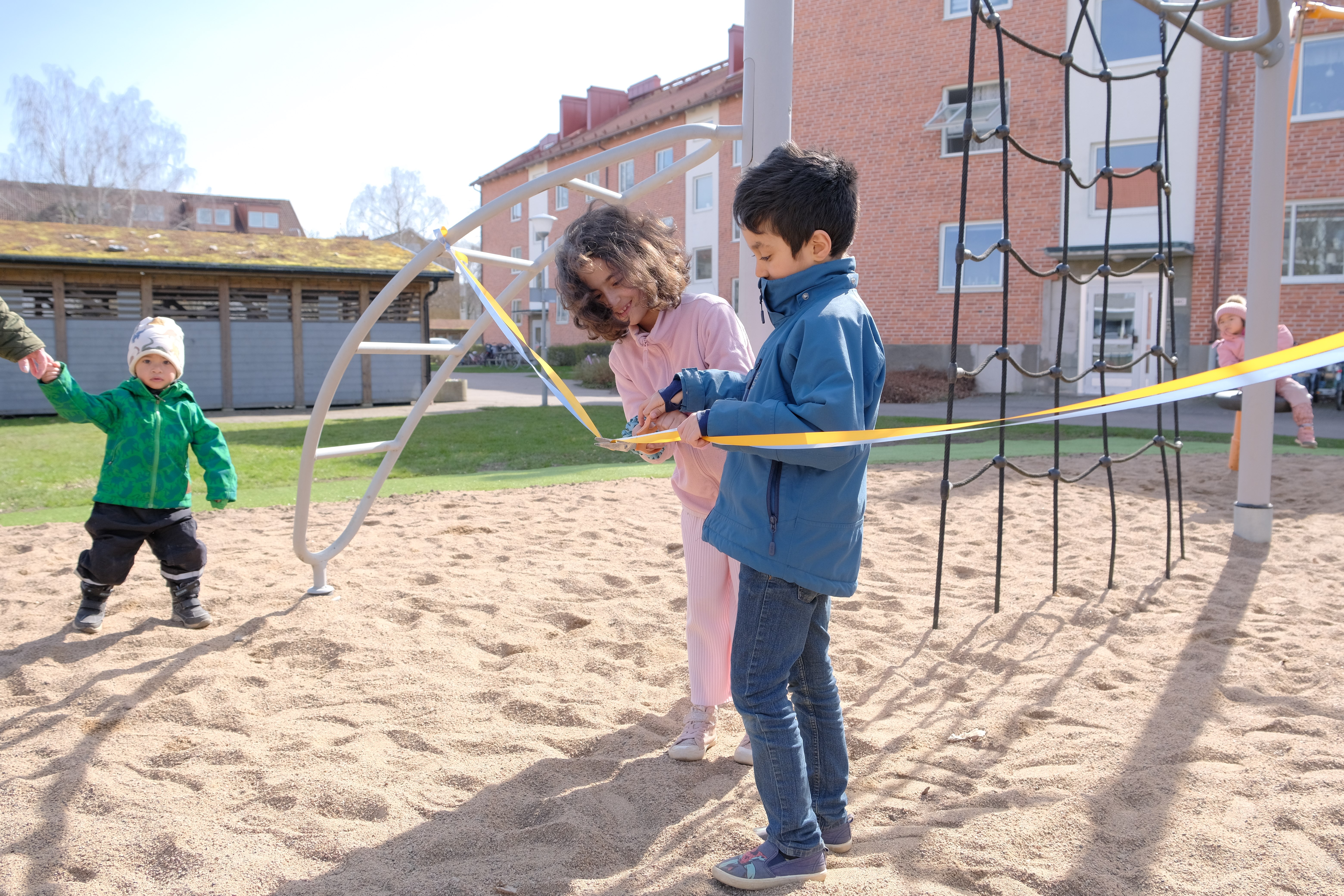 Två barn klipper invigningsband på lekplats